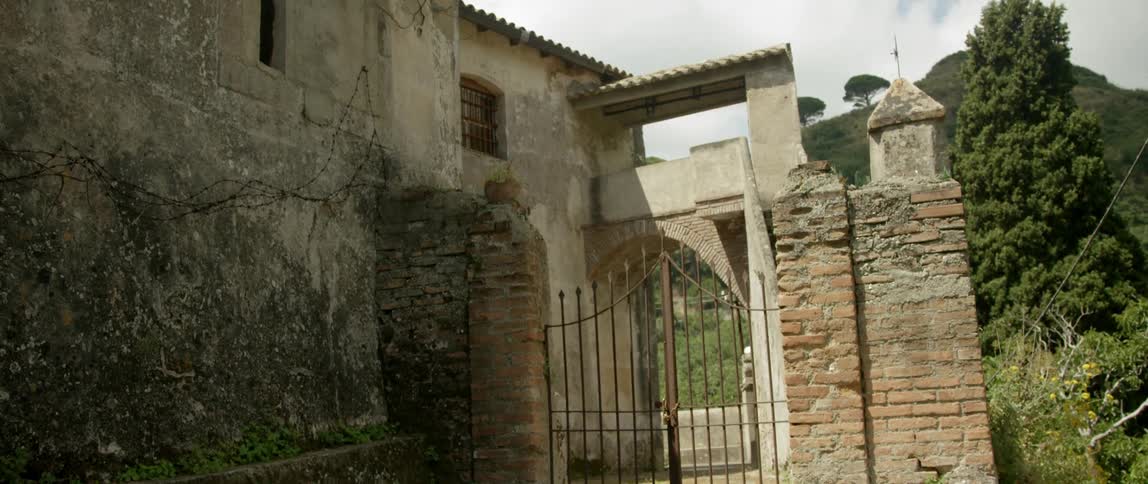 A fence leads to a stone building
