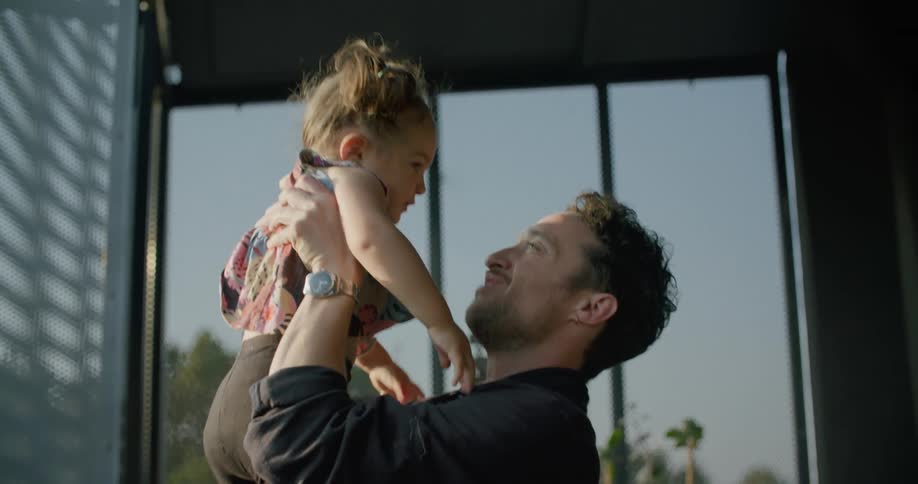 Father holds daughter and spins around laughing with her