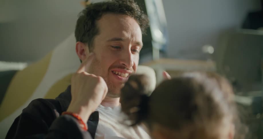 A man in a room talking to a girl with a wall in the background
