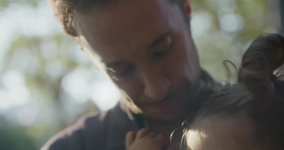 A father is holding his daughter outdoors in spring