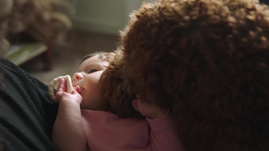 A furry dog licking a newborn in its fathers arms