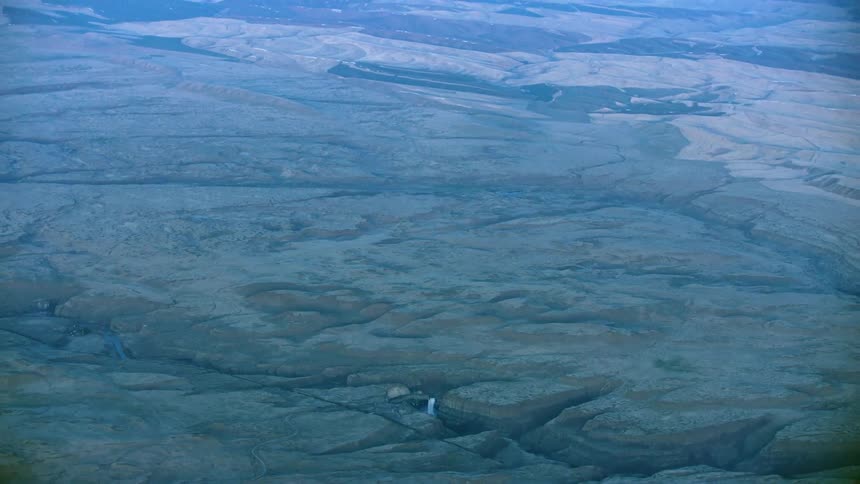 Slow zoom out reveal of Palouse Falls and the vast Palouse wheat growing region of Eastern Washington in late evening light from high above Earth