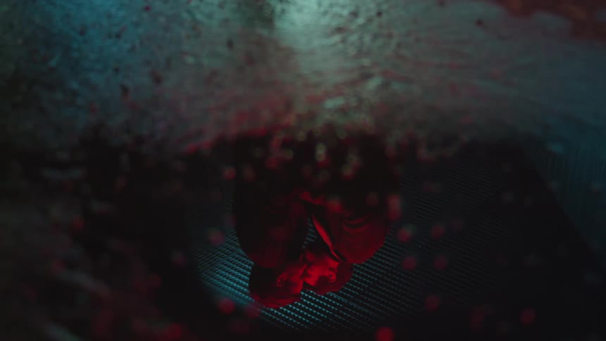 Two men kissing under red light in a reflection