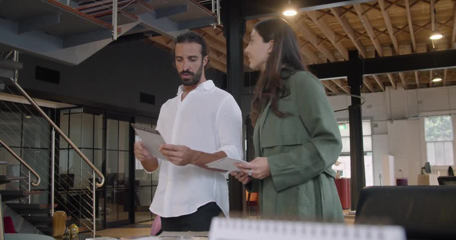 Two coworkers talking in an office while looking at a document