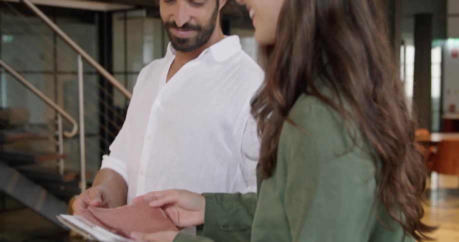 A man and woman smiling and talking while looking at a fabric sample