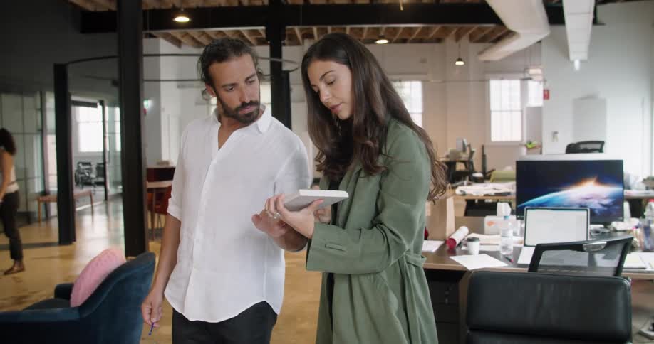 Two coworkers collaborating while standing in an office setting