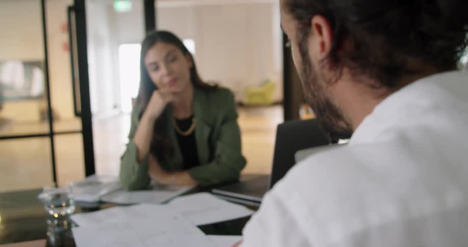 A man and a woman sitting at a desk with laptops
