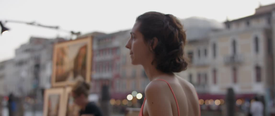 A woman walks past an art stand in a city
