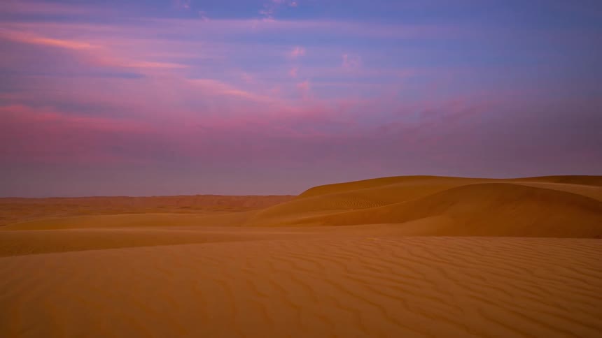 Clouds move over a desert and turn pink