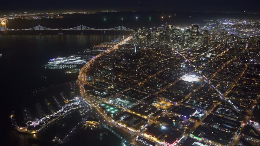 Aerial view of illuminated city with harbor next to river at night