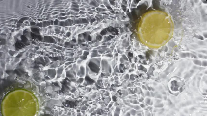 Two slices of citrus fruit glide across the surface of a shallow layer of clear water