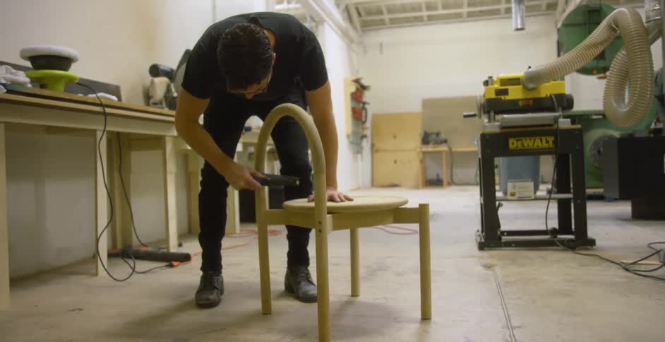 A carpenter sands a chair