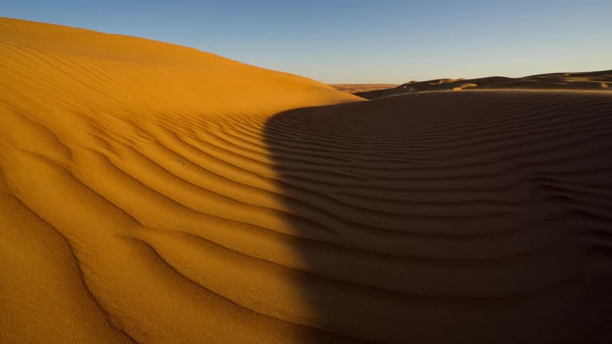 Time lapses in a barren desert with dunes from midday to dusk