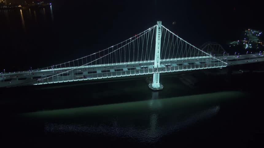 Aerial view of cars driving on a bridge over a large body of water at night