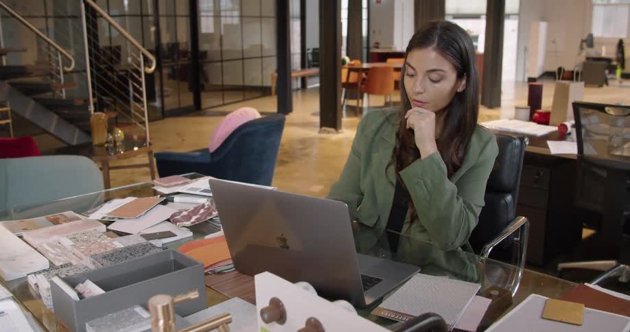 Woman sitting at the desk in an office working on a laptop