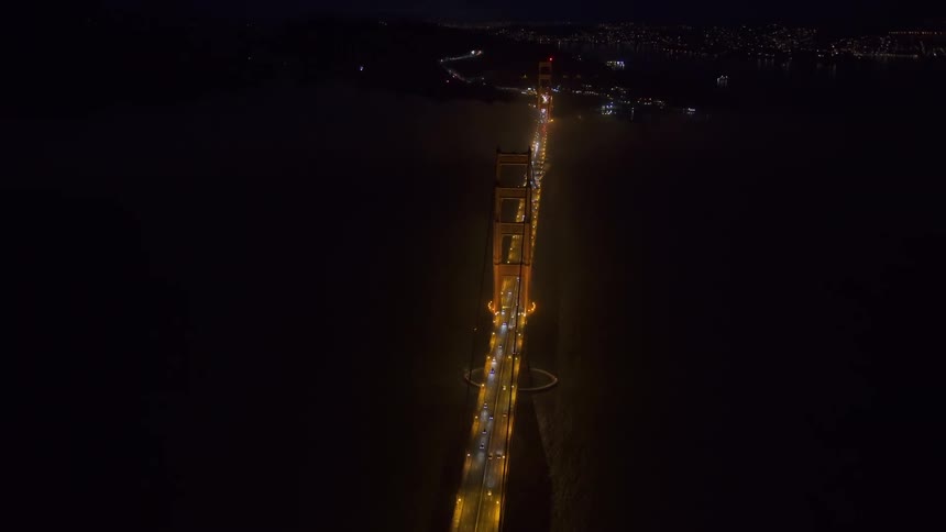 A bridge over a river with vehicles with a city skyline in the background
