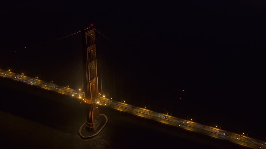 An aerial view of cars traveling over a large city bridge at night