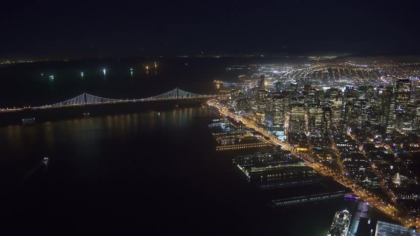 A vast river spanned by a suspension bridge in a metropolis at night
