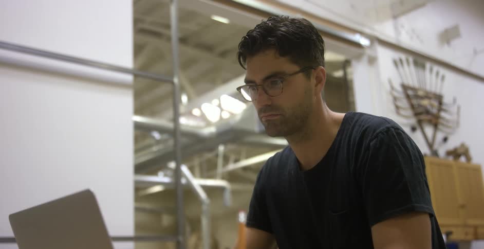 A man looking at his laptop in a workshop space
