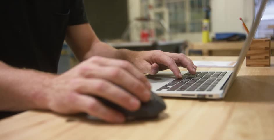 Man typing and using a mouse with a laptop computer