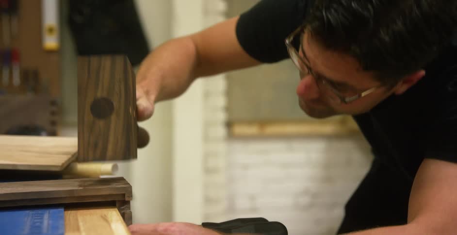 Carpenter hammers a piece of wood into place