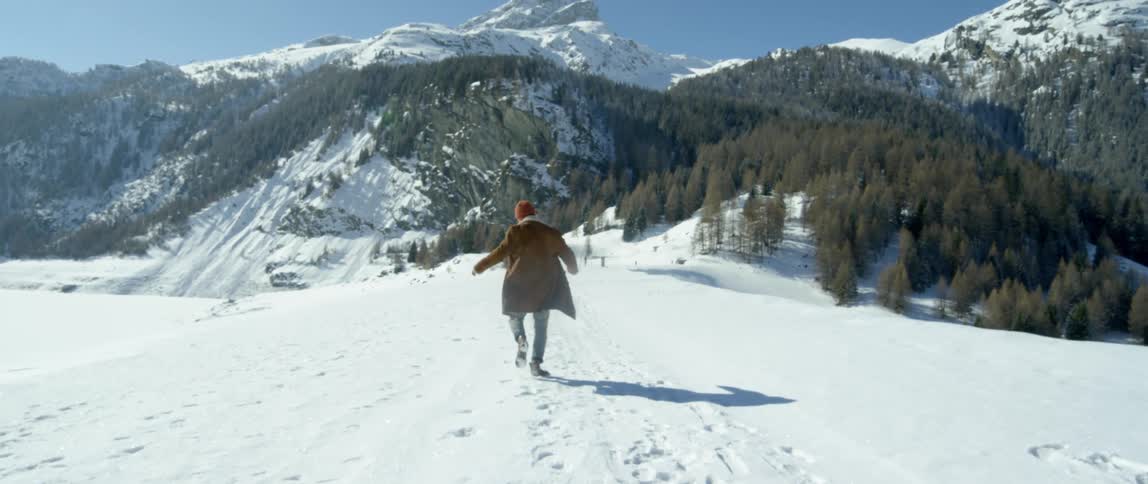 Man frolicking over the snow near the pine tree forest on the mountain range