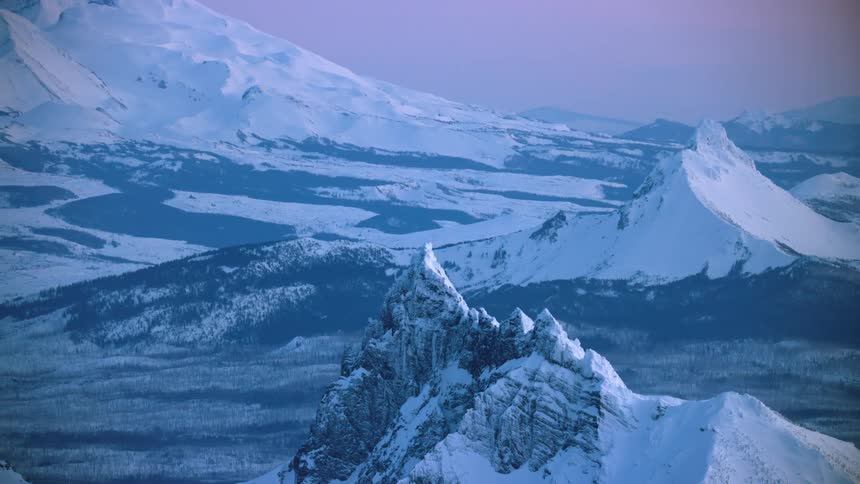 Mount Jefferson and Mount Bachelor rises for into the golden light of sunset deep in winter in this blue hour aerial from high above