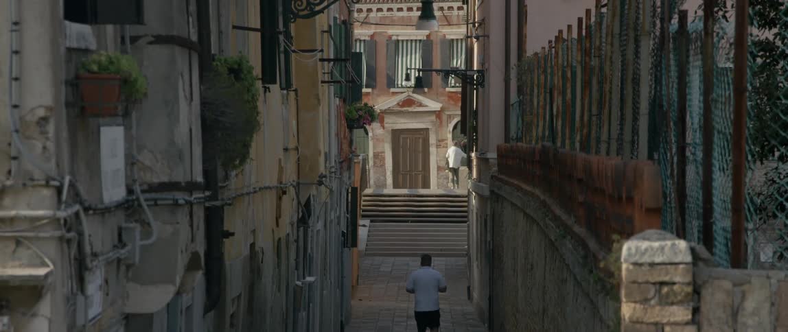 A man walks down an alley in a city