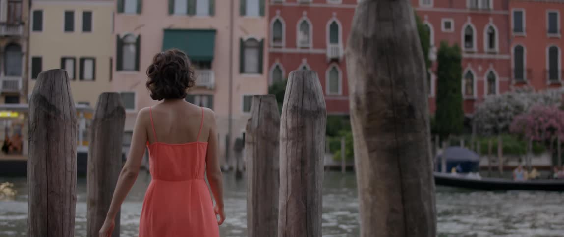 A woman in an orange dress walks on a dock