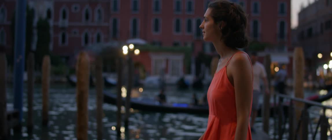A woman is walking along a pier at sunset