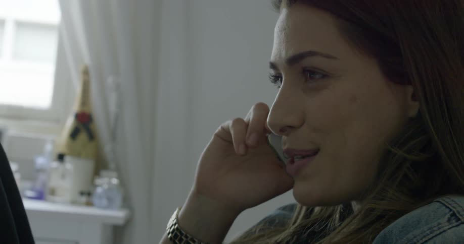 A woman talks on the phone in her room