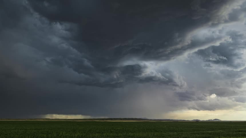 Dark storm clouds floating above a field during a rainstorm