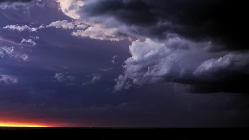 Lightning flashes as dark storm clouds move over land