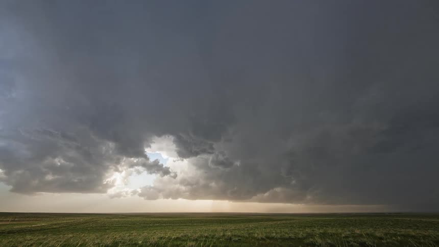 Large clouds floating over a rural field in the daytime