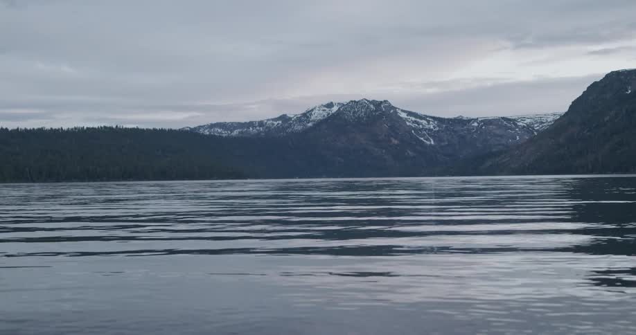 Mountains with snow in the distance over a lake in a forest at daytime
