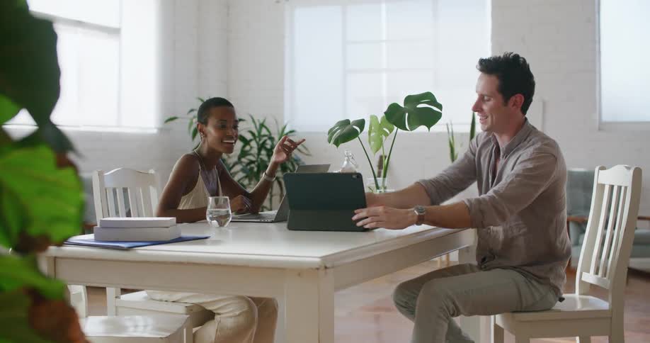 Two people look at devices and talk together
