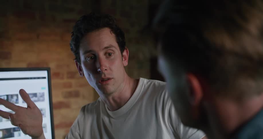 Two men that are talking to each other at a computer