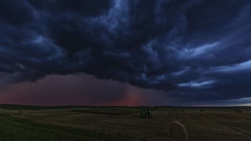 Time lapse of a large thundercloud sweeping across a farmland