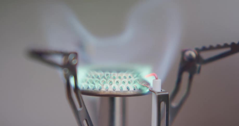 Blue flame burns from burner in metal frame