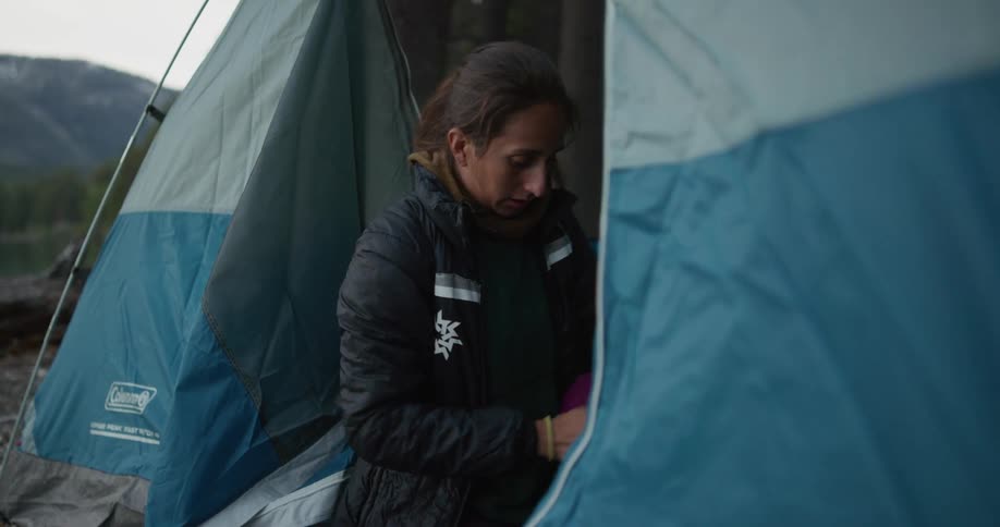 A woman is packing her stuff away in the tent