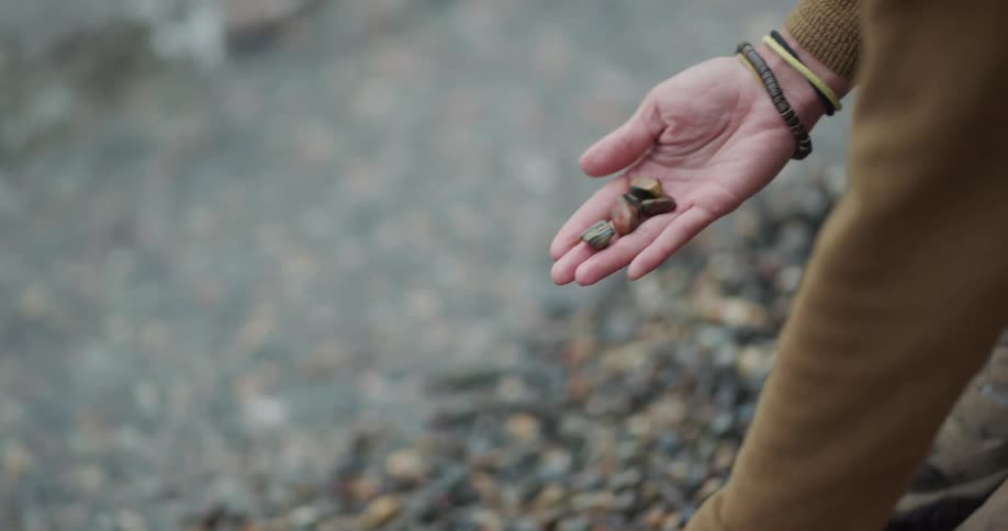 A woman picking up rocks on the edge of a stream