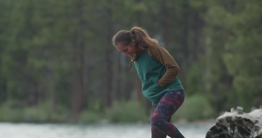 A happy woman standing at a lakes shoreline in the wilderness