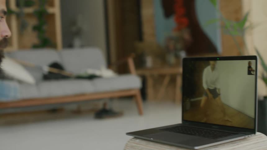 Yoga teacher supervises a student on an online class through a laptop