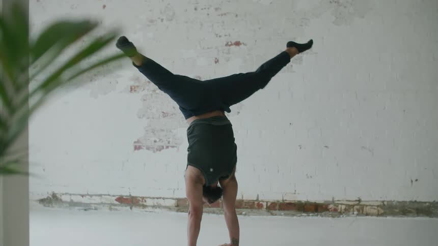 A man moves from a crouching position into a hand stand