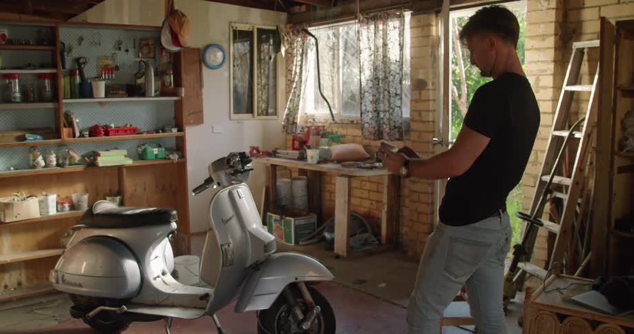 Man takes pictures of a scooter vespa parked inside the garage at home