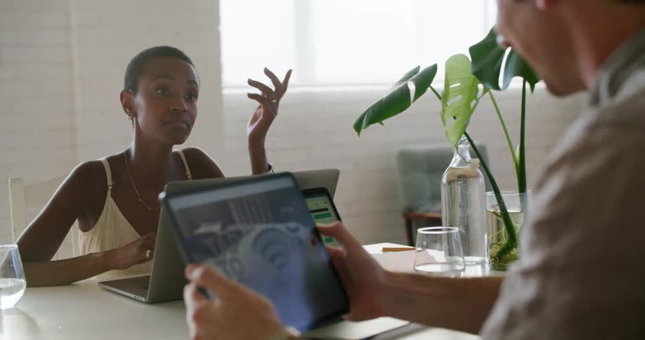 Coworkers in a meeting at the office working with tablets and laptops