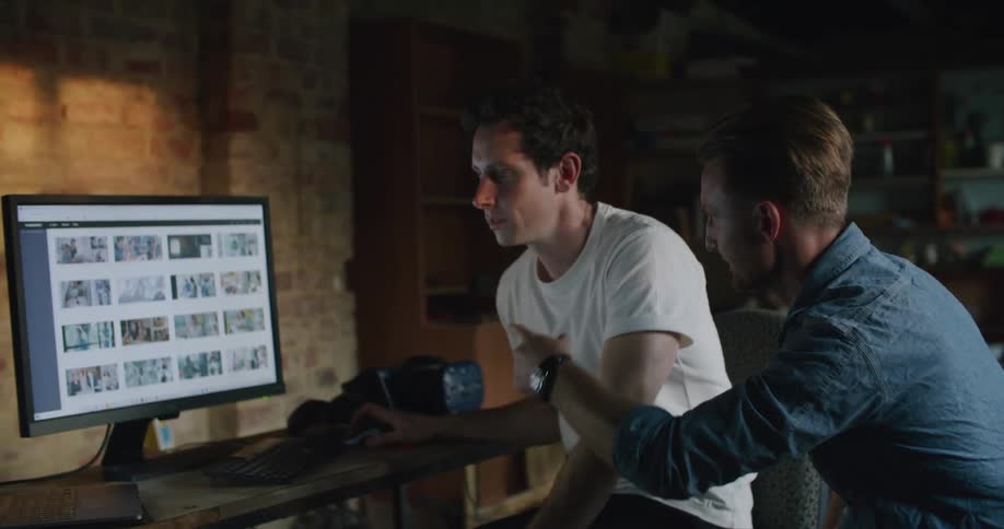 Two men talking and looking at a computer