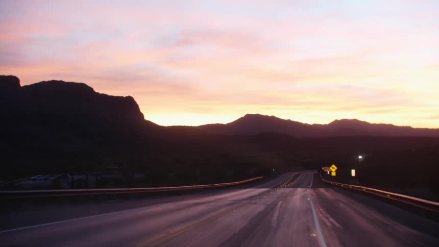 Driving down a road at sunset