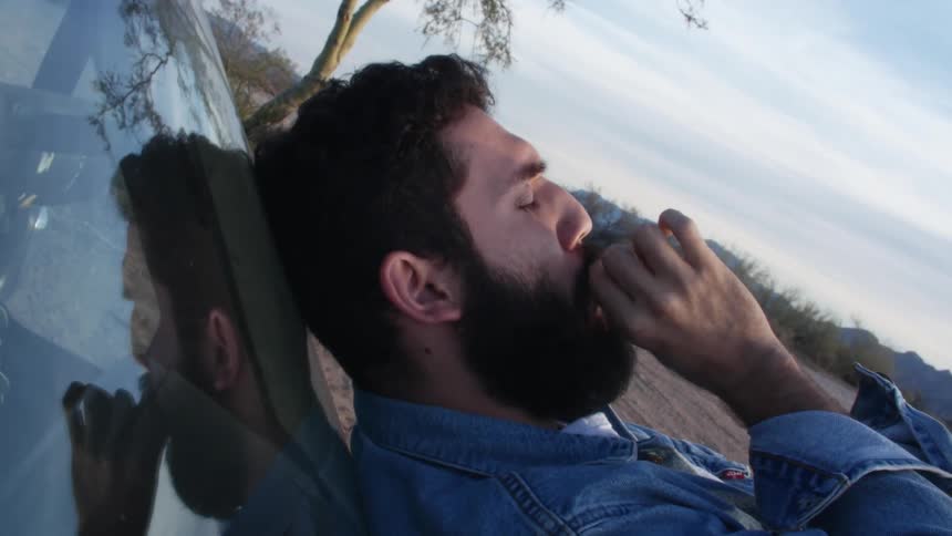 A man is smoking on top of his car