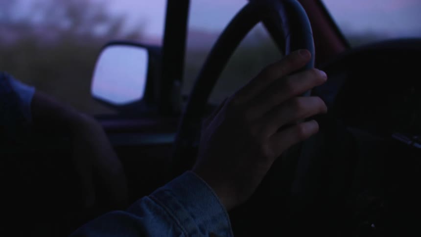A man drives with one arm on the window of his vehicle as he passes a canyon